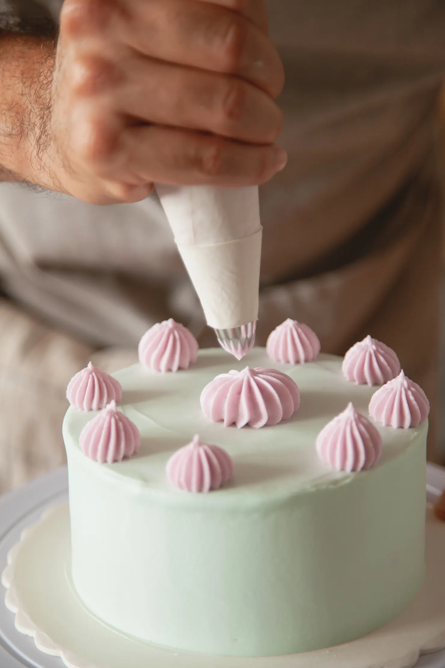 Cake being decorated with pink cream